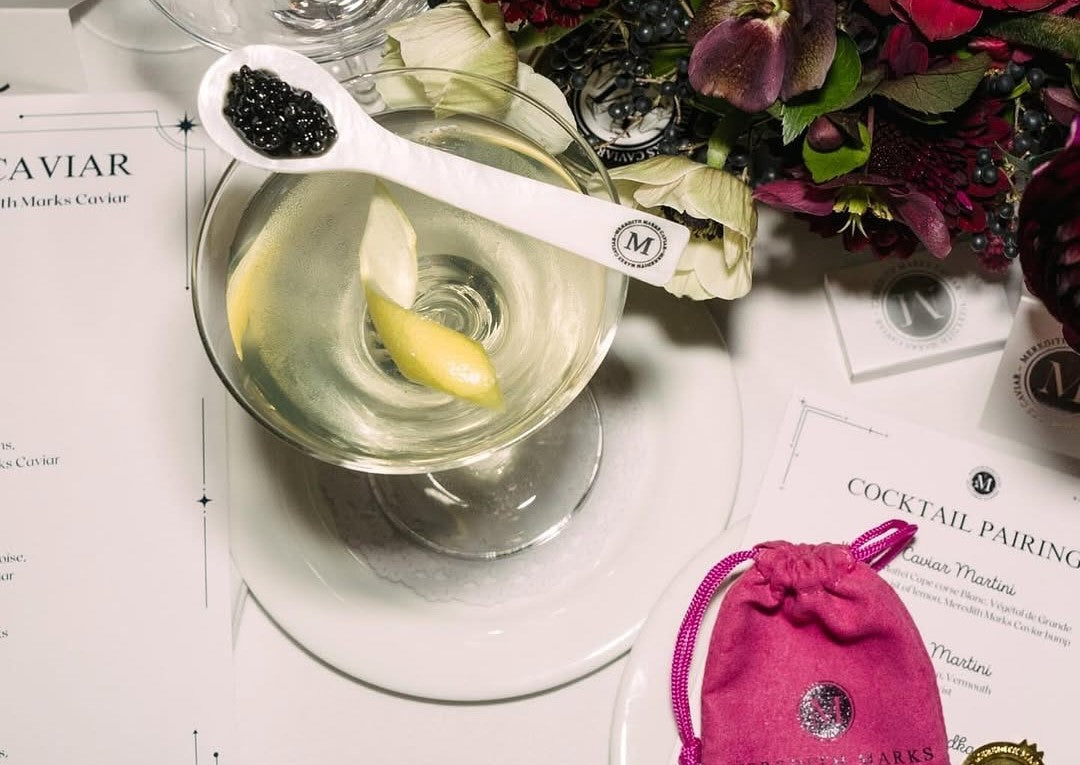 Meredith Marks’ mother-of-pearl spoon with caviar and a cocktail glass on a desk decorated with flowers.