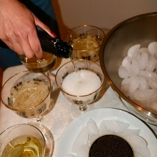 A dinner table set for caviar tasting, featuring wine glasses, a tin of Meredith Marks Caviar on ice, and elegant tableware in a Texas dining setting.