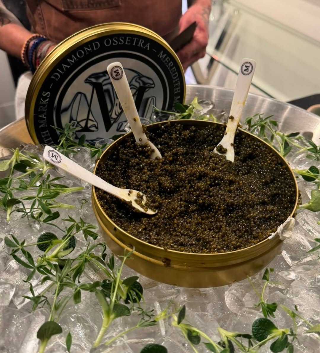 Meredith Marks Diamond Ossetra caviar tin on ice with mother-of-pearl spoons, preserving freshness.