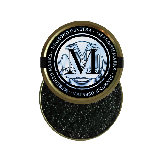A tin of Meredith Marks Diamond Ossetra caviar with black pearls and a logo featuring an 'M' design on the lid.